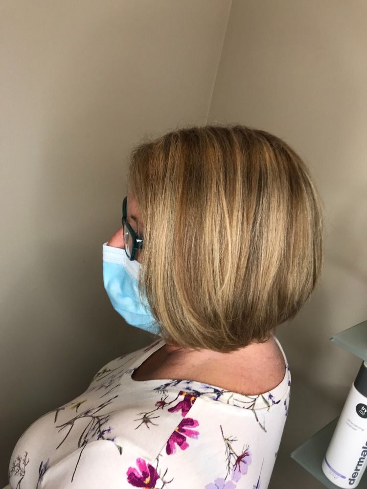 A woman wearing a face mask and glasses is sitting in a room.