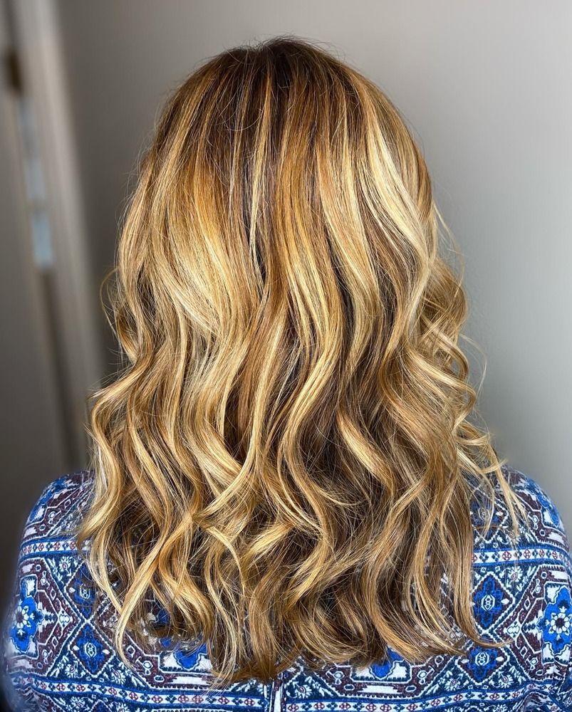 The back of a woman 's head with long wavy blonde hair.