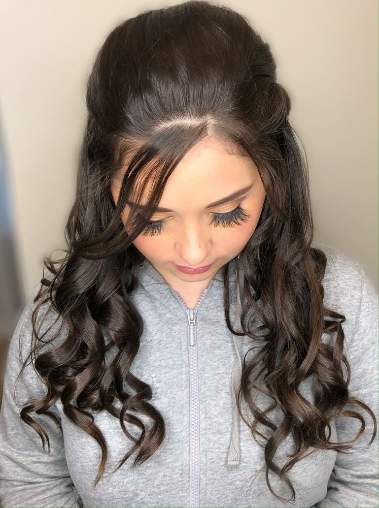 A woman with long curly hair is wearing a gray hoodie.