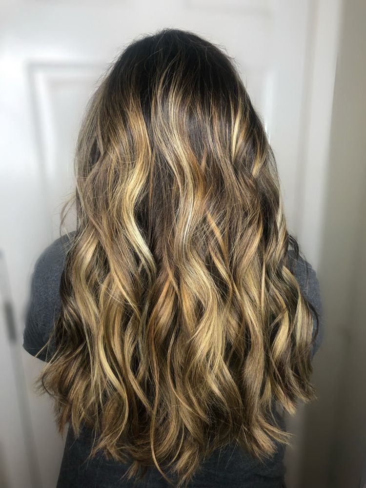 A woman with long wavy hair is standing in front of a door.