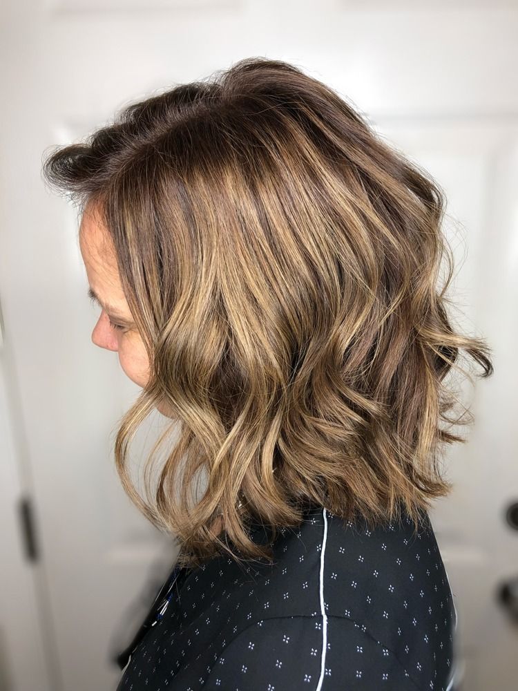A woman with short wavy brown hair is wearing a black polka dot shirt.