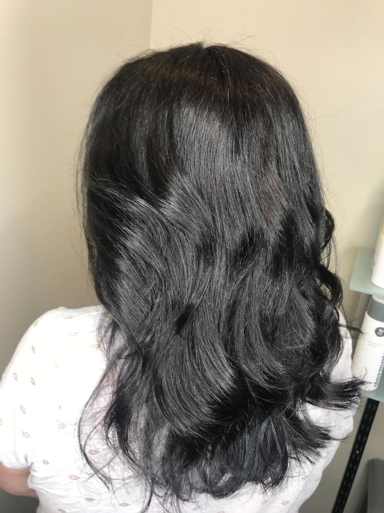 A woman with long black hair is wearing a white shirt.