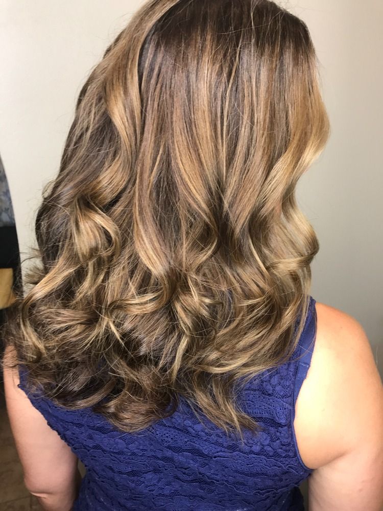 A woman with long brown hair is wearing a blue dress.