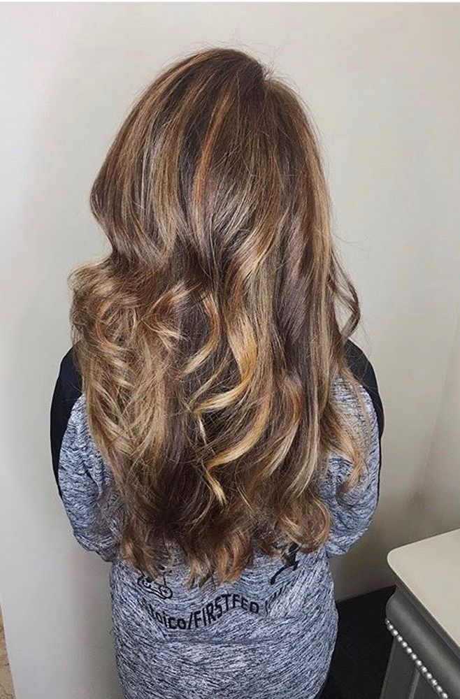 A woman with long brown hair is wearing a blue sweater.