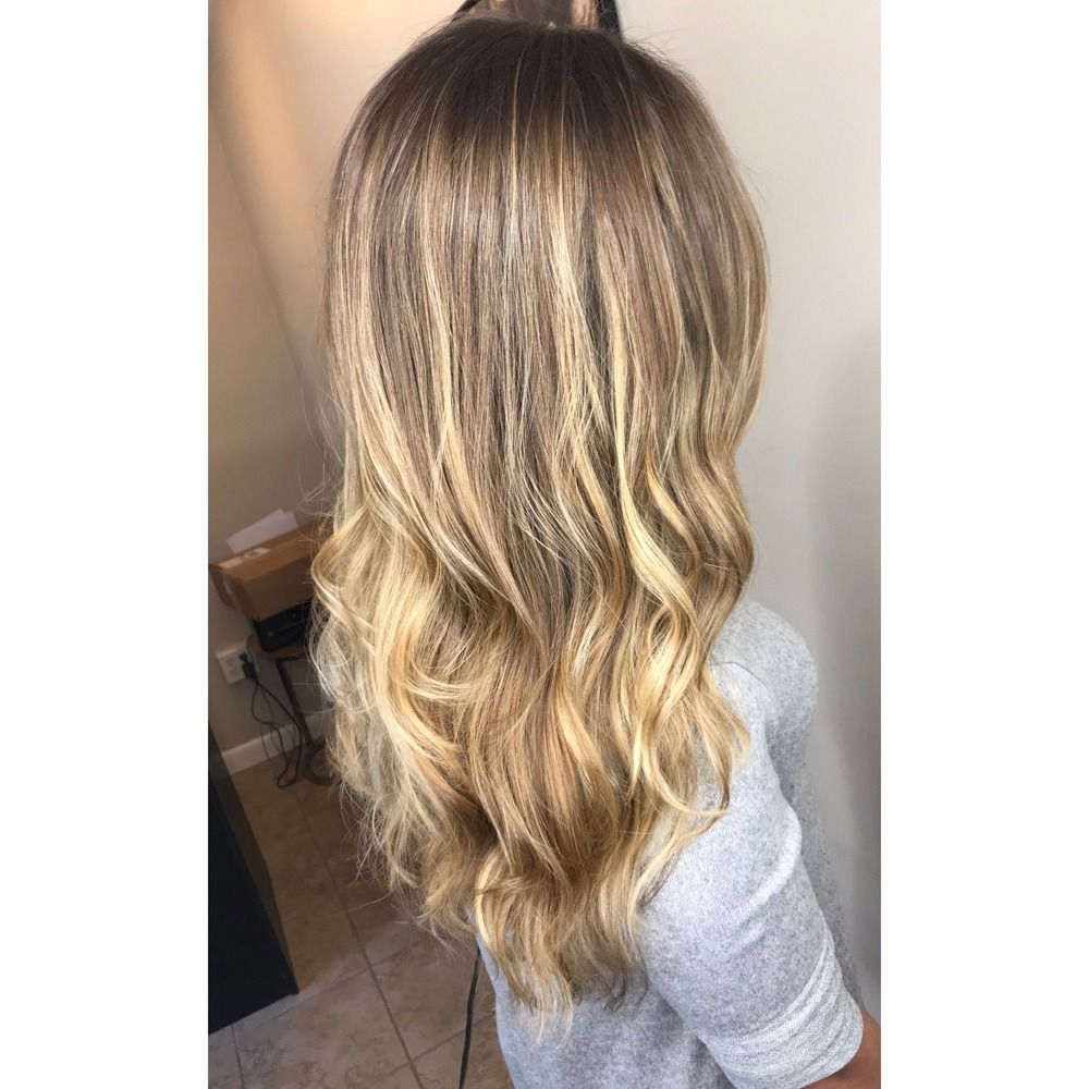 A woman with long blonde hair is wearing a grey shirt.