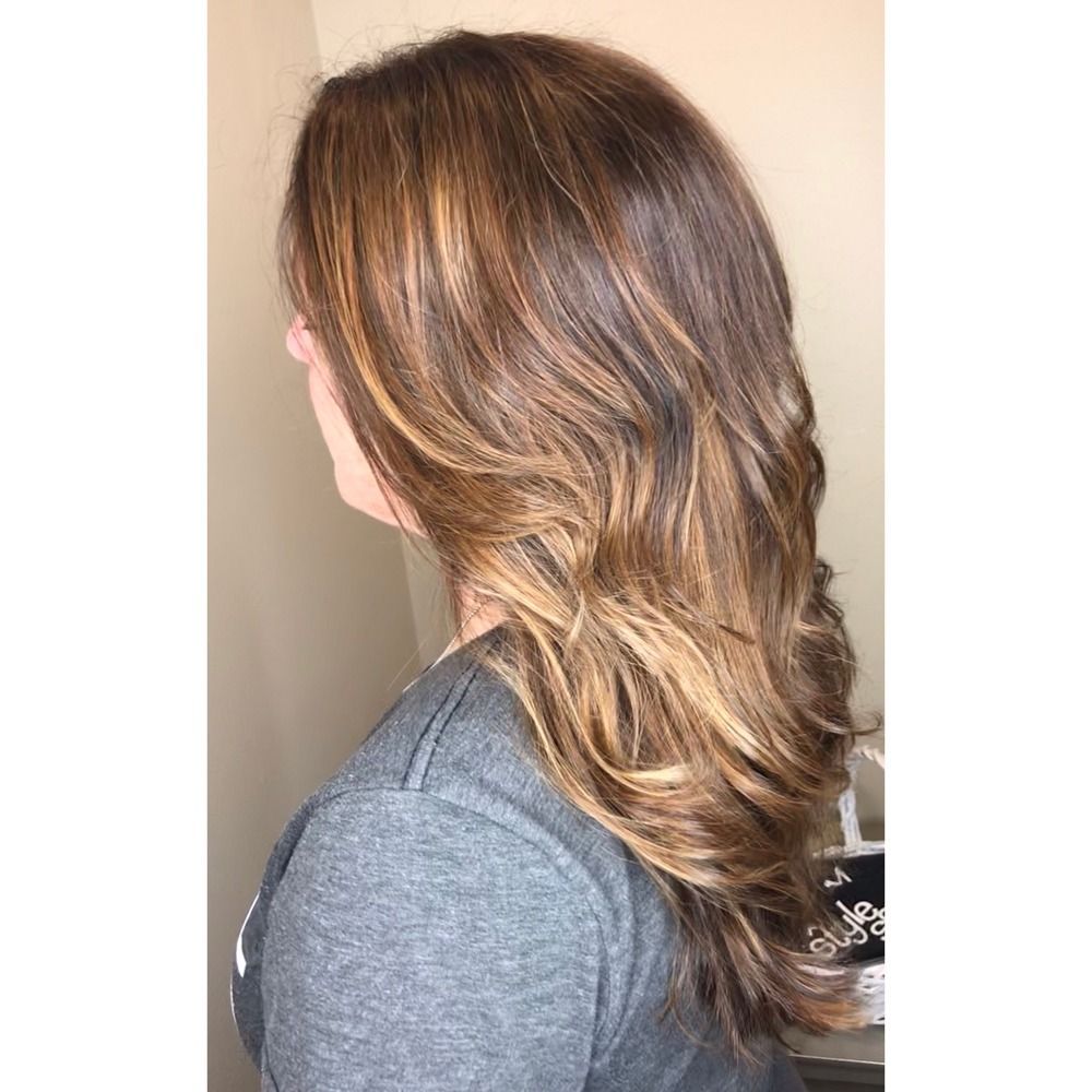 A woman with long brown hair is wearing a gray shirt.