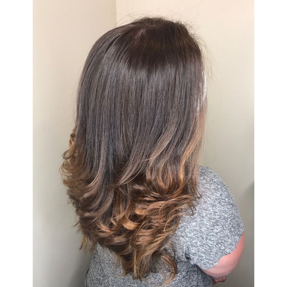 A woman with long brown hair is wearing a grey shirt.