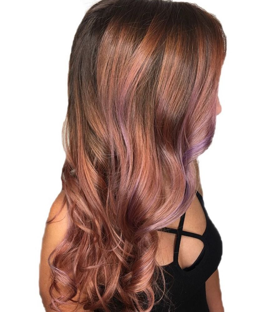 A woman with long brown hair and purple highlights is wearing a black tank top.