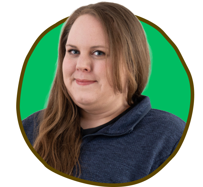 Kvinde med langt brunt hår, smilende, iført en blå sweatshirt, sat i en grøn cirkel.