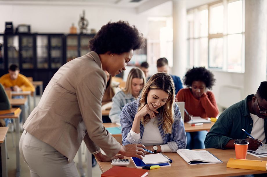 a teacher is helping a student with her homework in a classroom