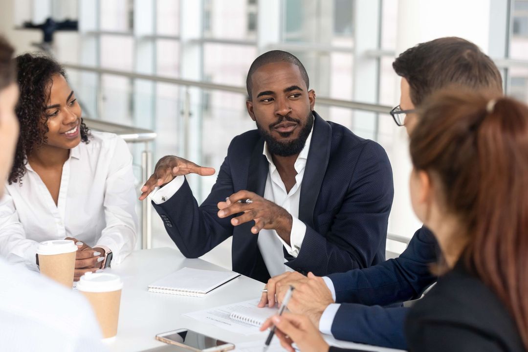 a group of people are sitting around a table having a meeting