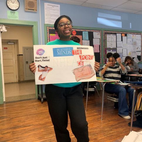 a girl is holding a sign in a classroom 