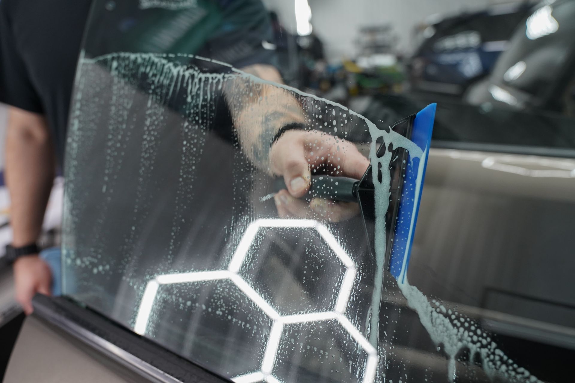 A man is applying tinted glass to a car window.