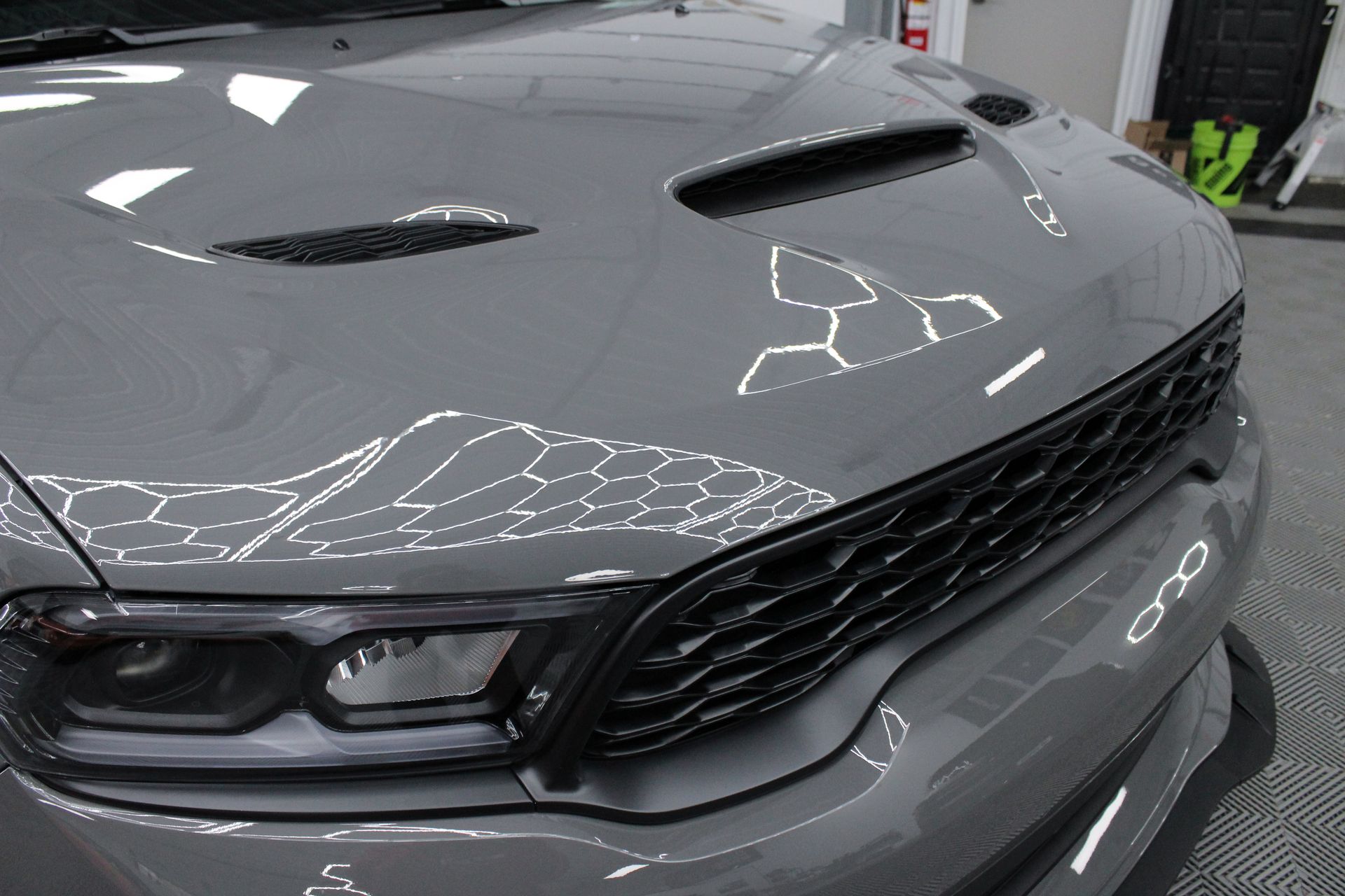 A man is cleaning a car with a cloth in a garage.