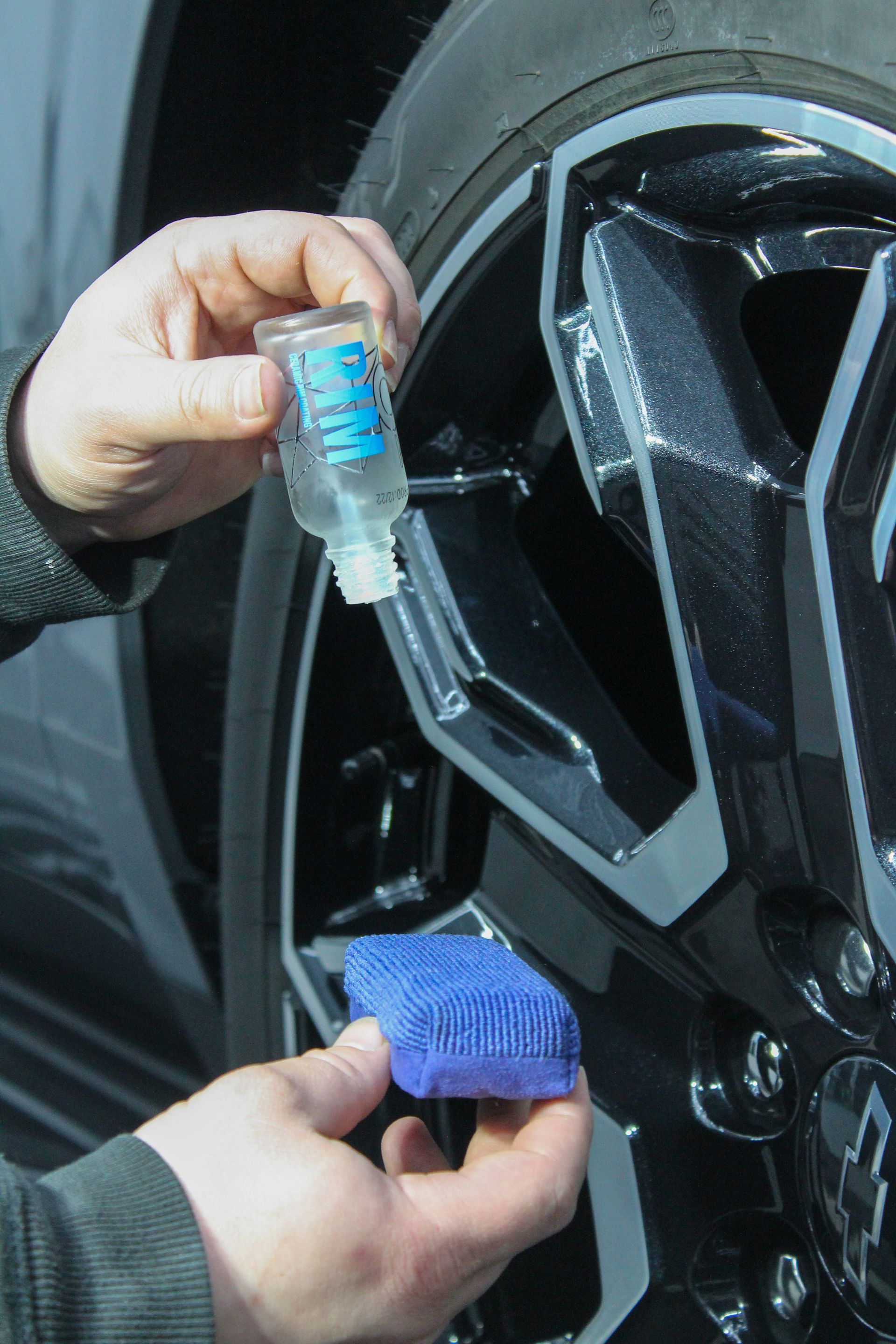 A person wearing black gloves is holding a blue sponge in their hand.