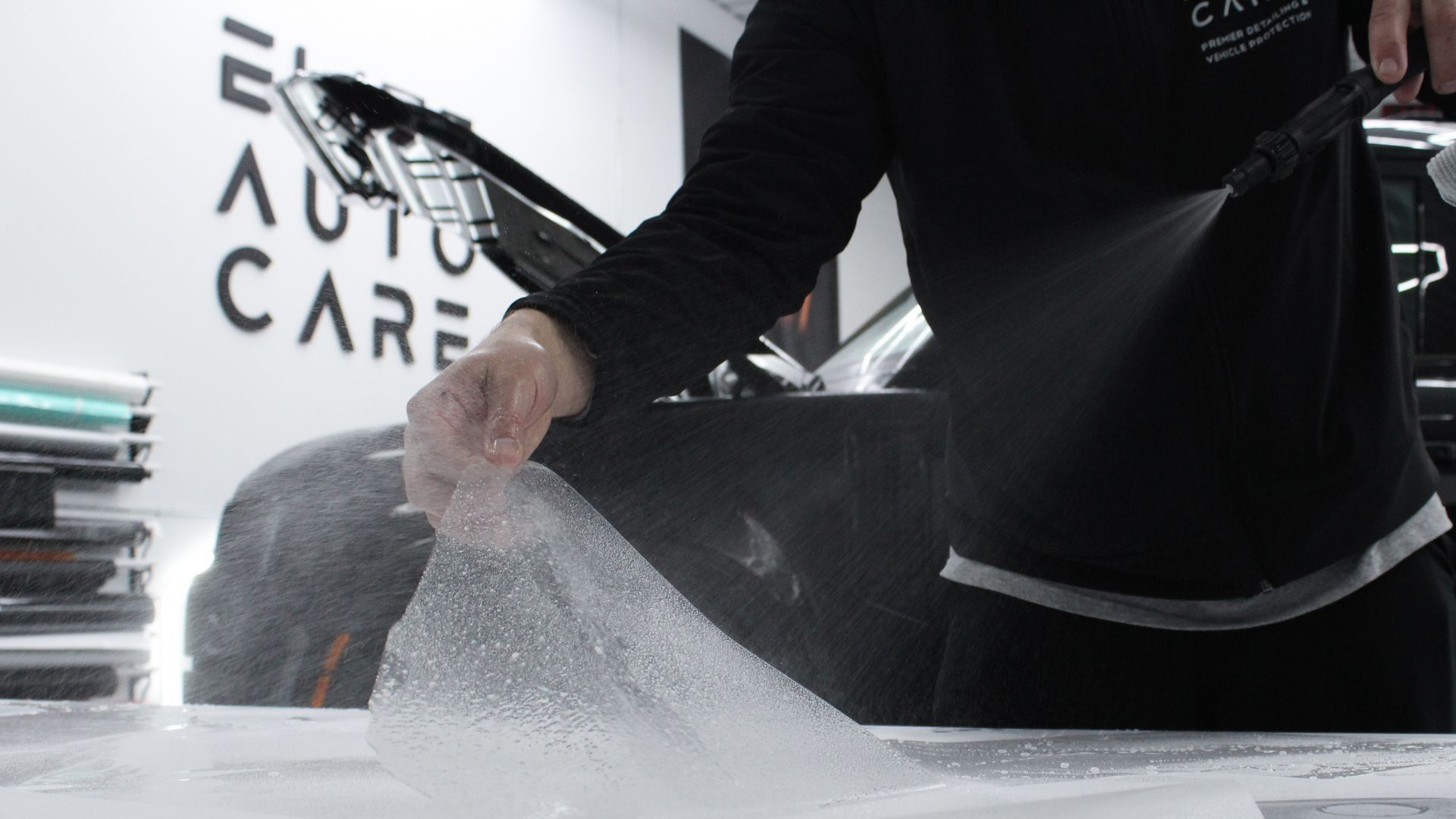 A man is applying a film to the windshield of a car.