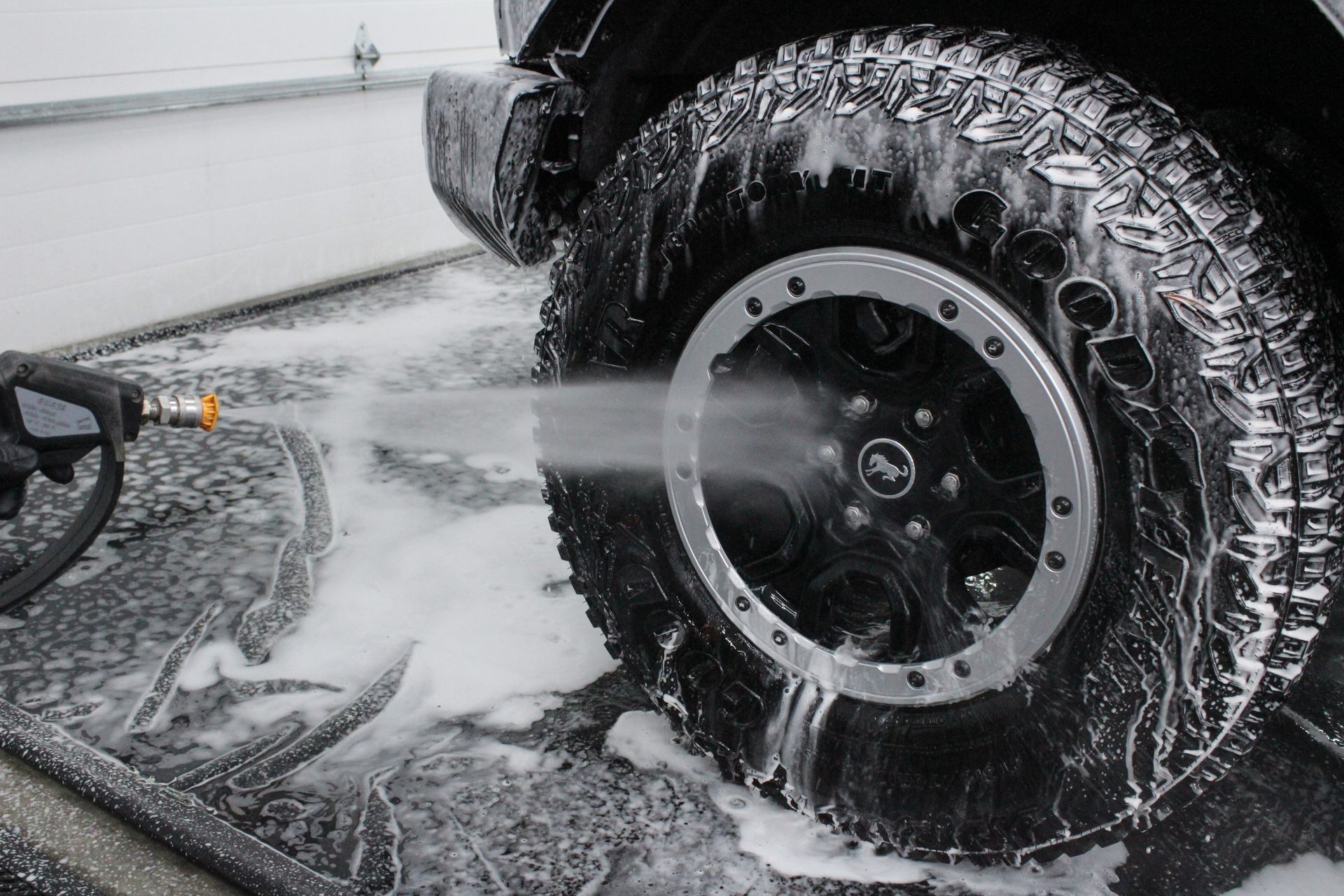 A person is washing a tire with a high pressure washer.