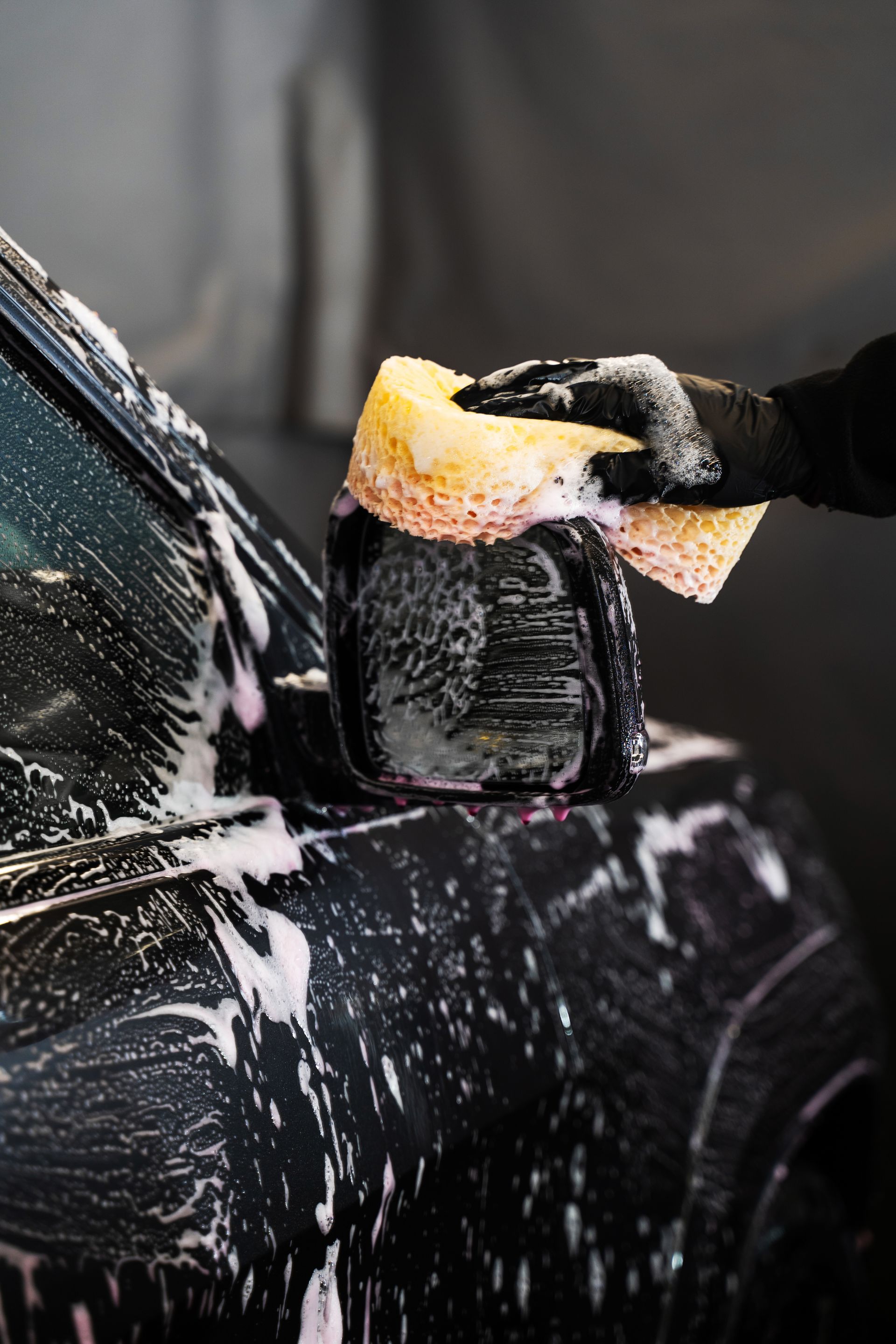 A person is washing a car with a sponge.