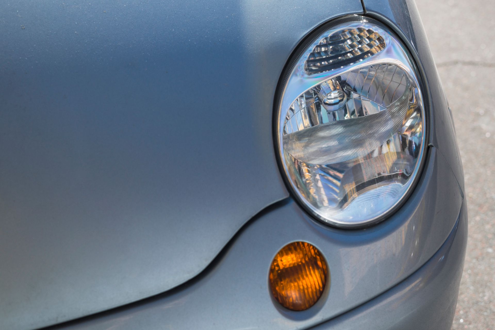A close up of a car 's headlight on a road.