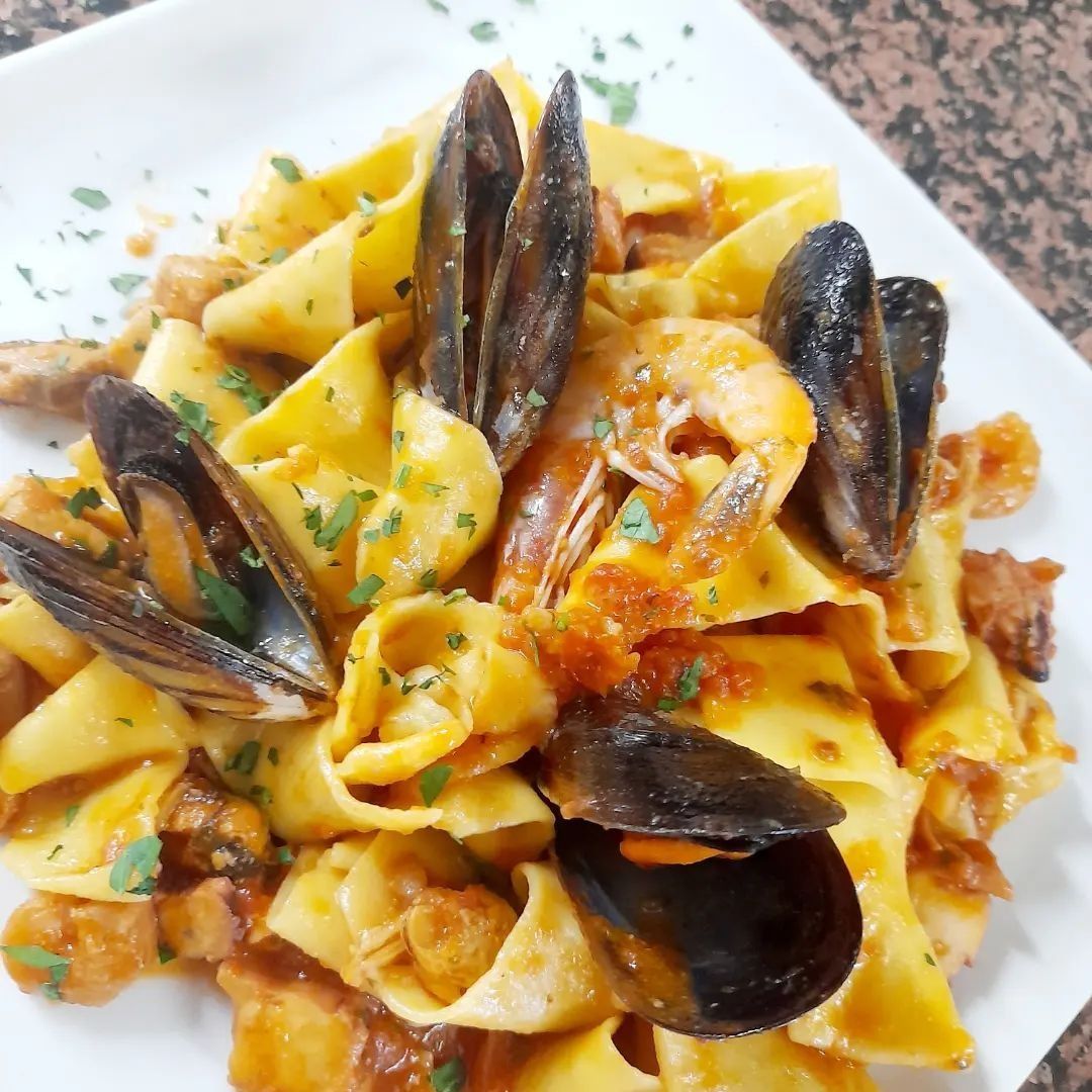 Piatto di pasta con cozze, gamberi e salsa di pomodoro.
