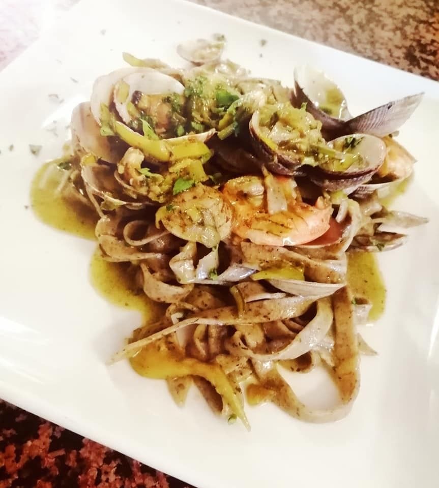 Piatto di pasta con vongole, gamberi e salsa su un piatto bianco.