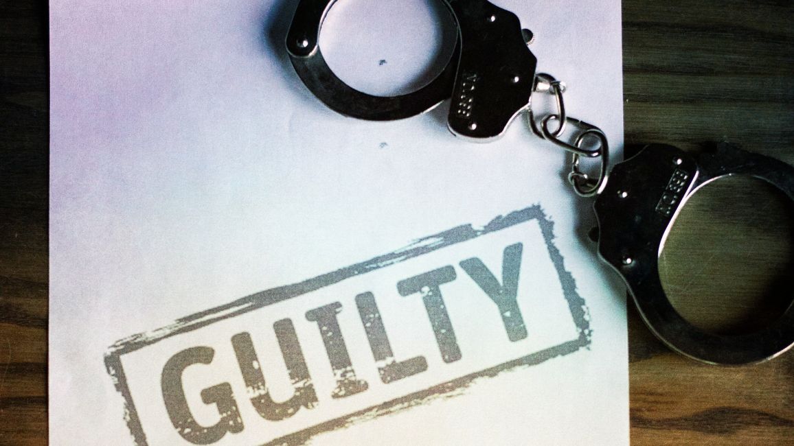a pair of handcuffs sitting on top of a piece of paper that says guilty