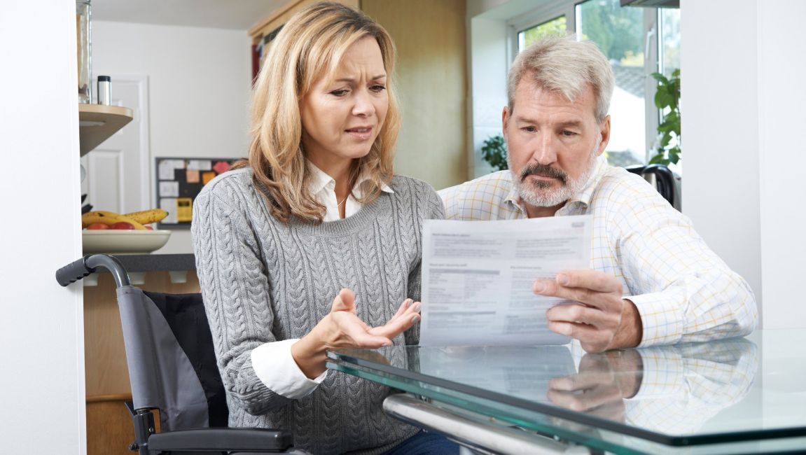 a man and a woman are sitting at a table looking at a piece of paper about disability.