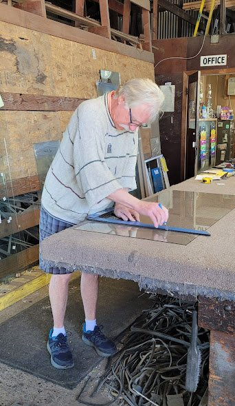 A man is measuring a piece of wood with a tape measure.