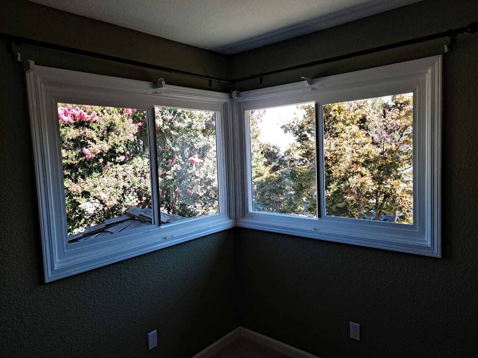 A room with two windows and a view of trees.