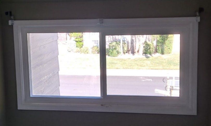 A window with a view of a yard and trees in a room.