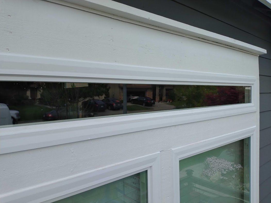A close up of a window on a house with a reflection of a car in the window.