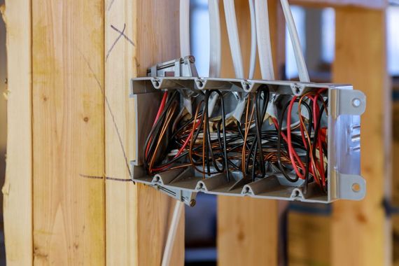 A box of wires is hanging from a wooden wall.