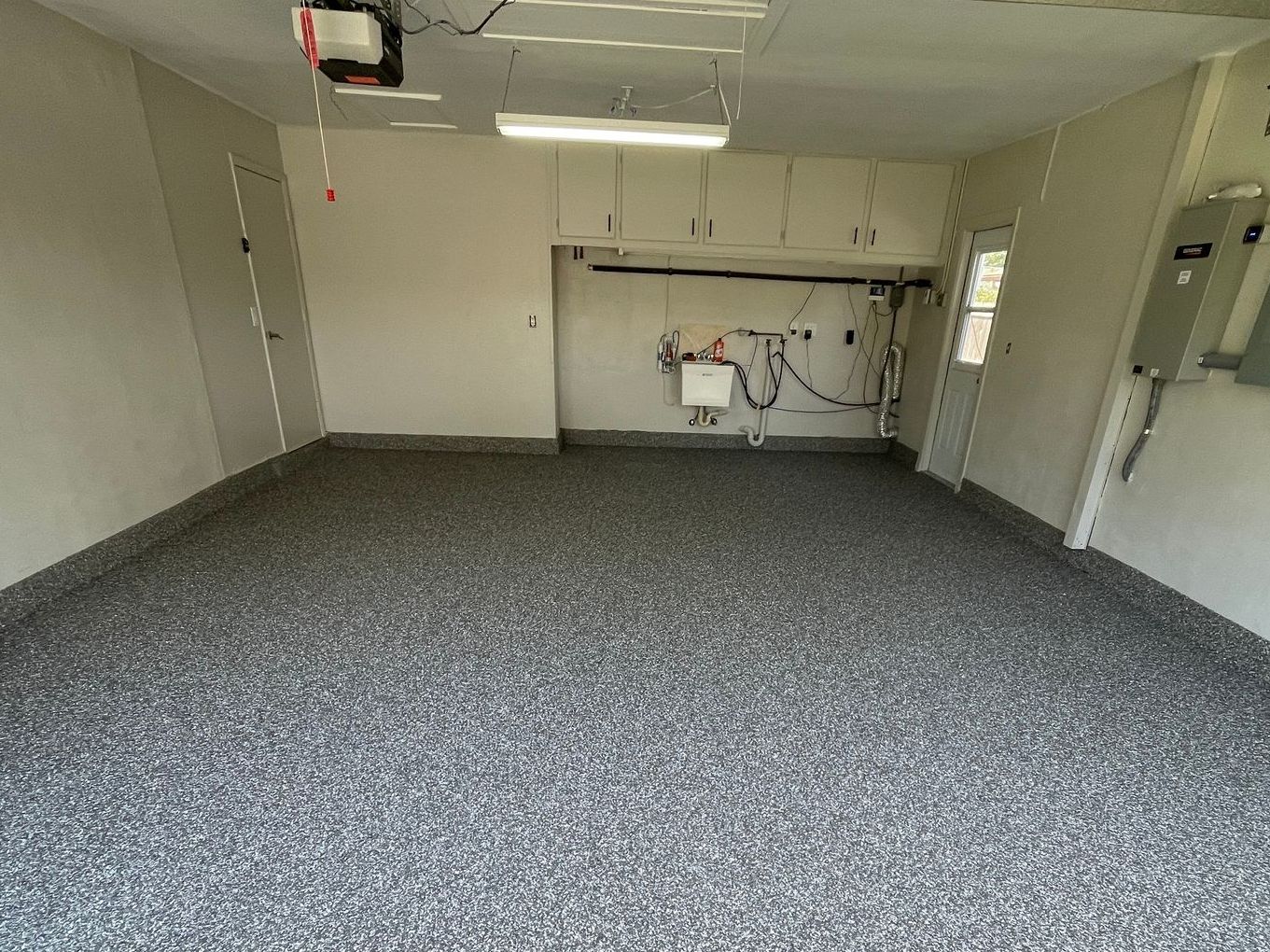 Clean and empty garage with newly applied concrete coating on floor and bottom part of walls
