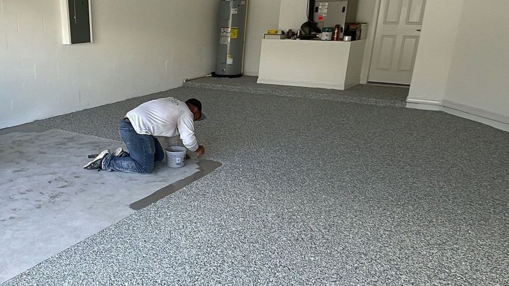 Atlantis Concrete Coating installer applying 100% polyurea base coat on garage floor