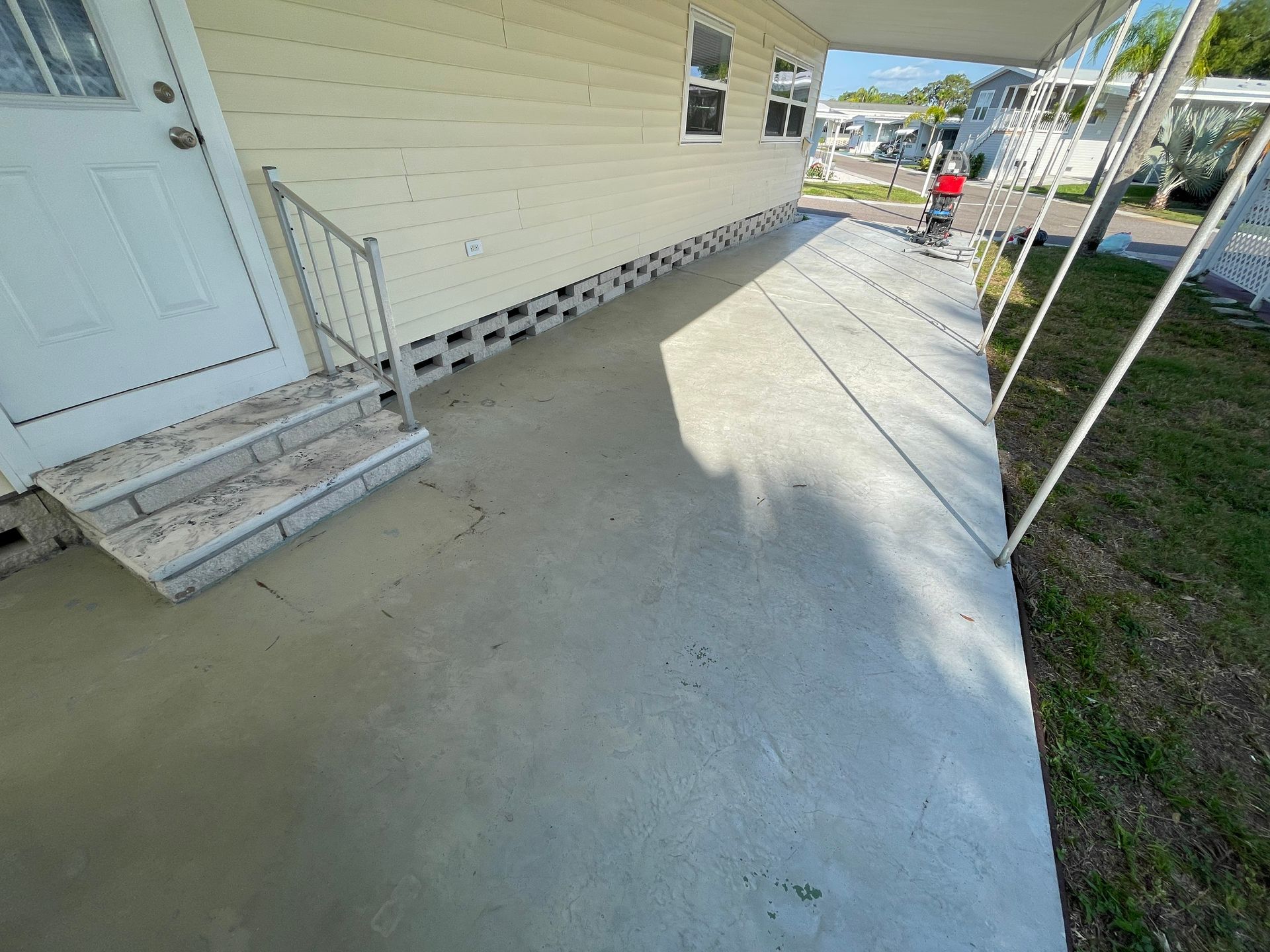 Stained and bare concrete driveway under carport