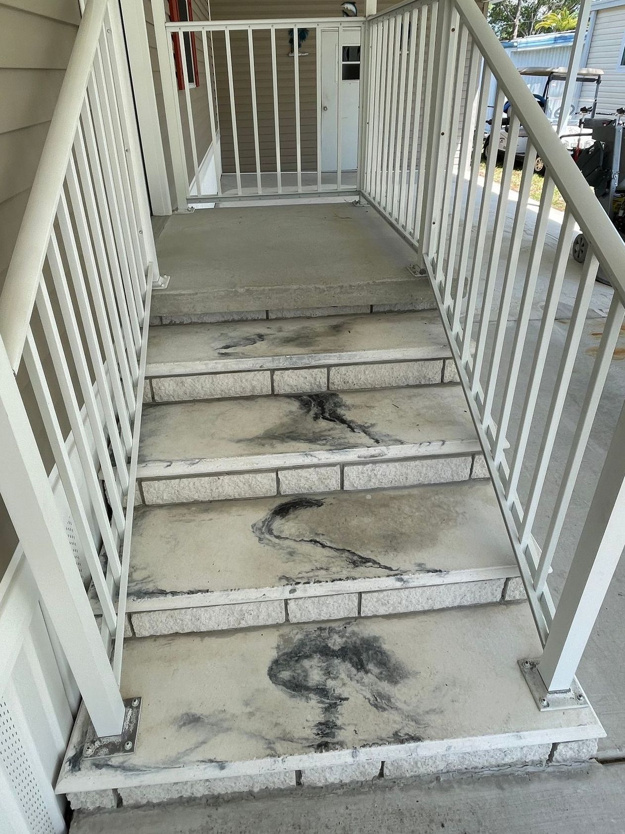 Bare concrete steps leading from driveway to front entrance of a house