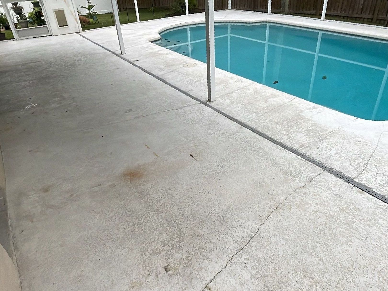 Cracked and stained bare concrete pool deck 