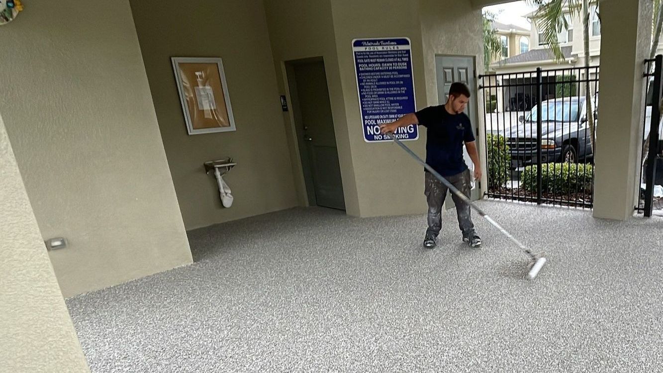 Atlantis Concrete Coating installer using roller to evenly distribute flake on concrete patio