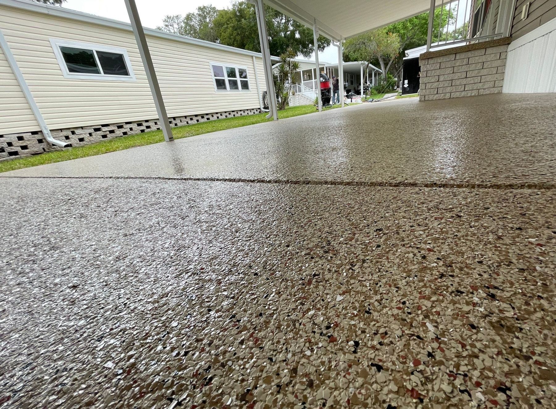 A concrete patio resurfaced and coated with warm-toned flake and polyurea/polyaspartic coating