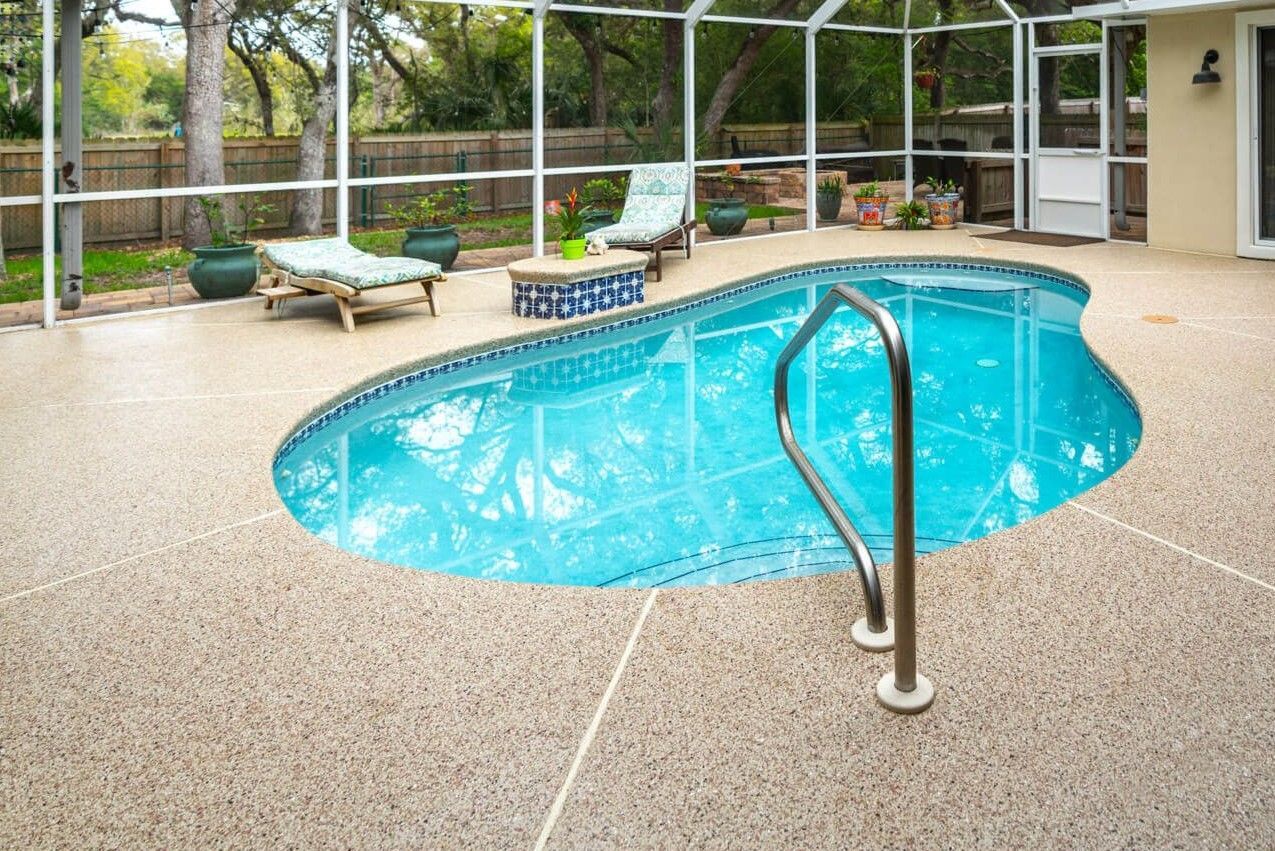 A small in ground pool surrounded by a concrete pool deck with a new neutral-toned coating