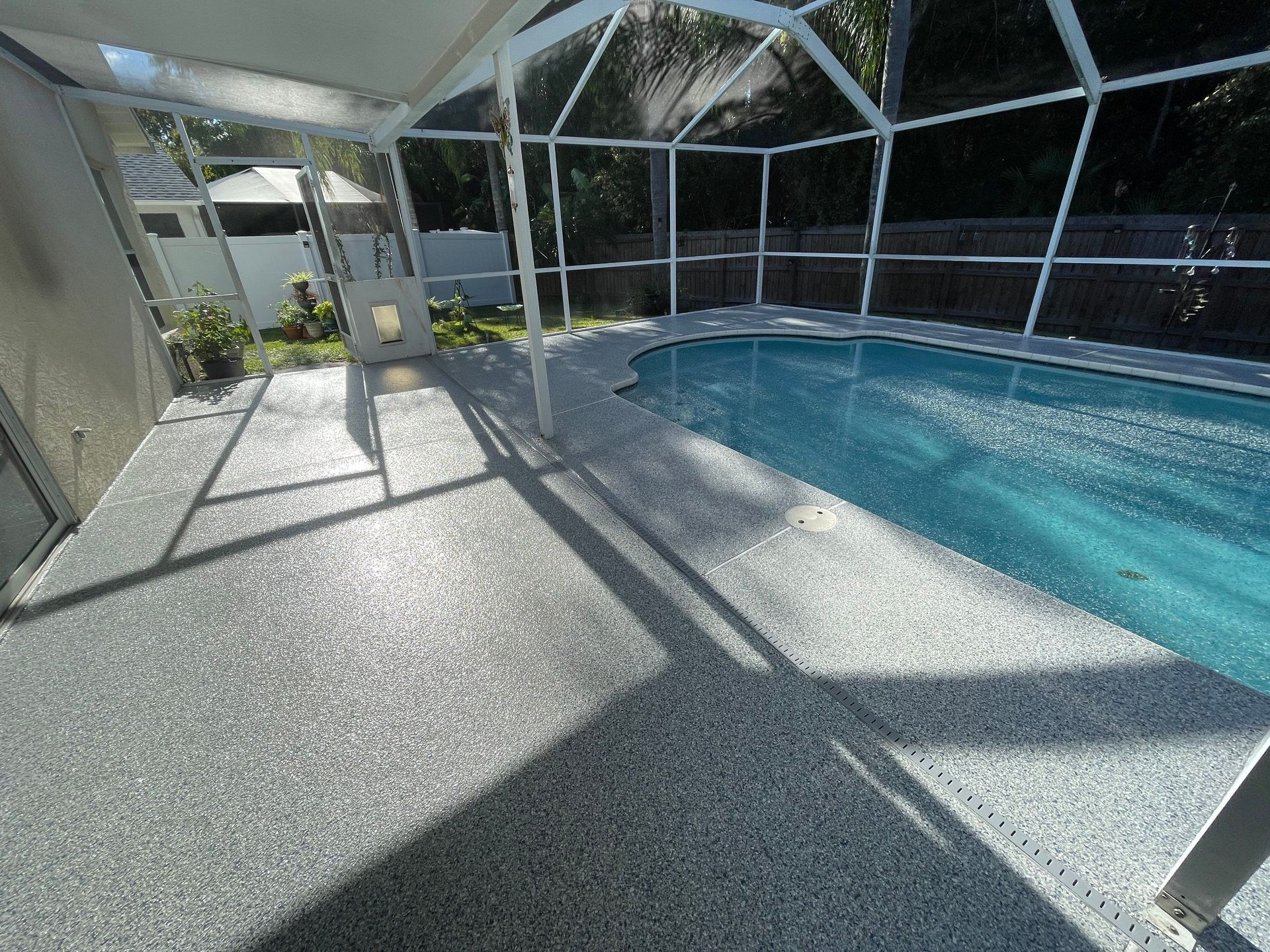 New concrete coating installed on a concrete pool deck surrounding turquoise water