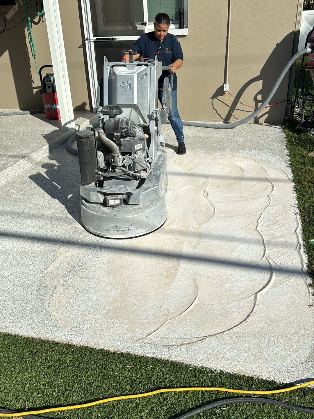 Atlantis Concrete Coating installer using industrial floor grinder to resurface concrete patio