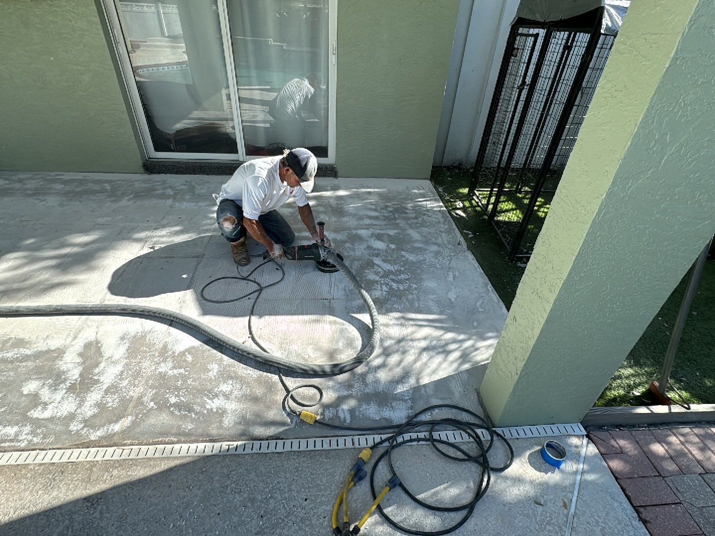 Atlantis Concrete Coatings installer using hand grinder to resurface concrete patio