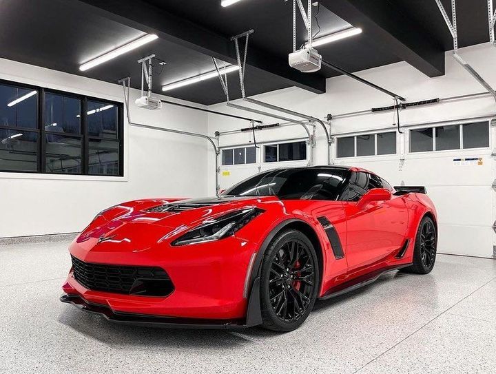 Red and black sports car parked over freshly coated garage floor