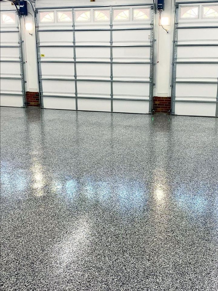 Gleaming black and white flake concrete floor coating inside a brightly lit garage