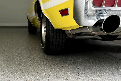 Vintage yellow sports car parked in garage with neutral-toned concrete coating on floor