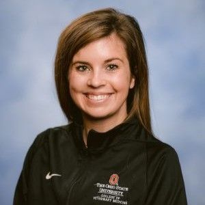 a woman in a purple hat is holding a monkey on her shoulder .