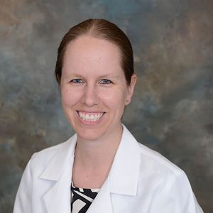 a woman in a white lab coat is smiling for the camera .