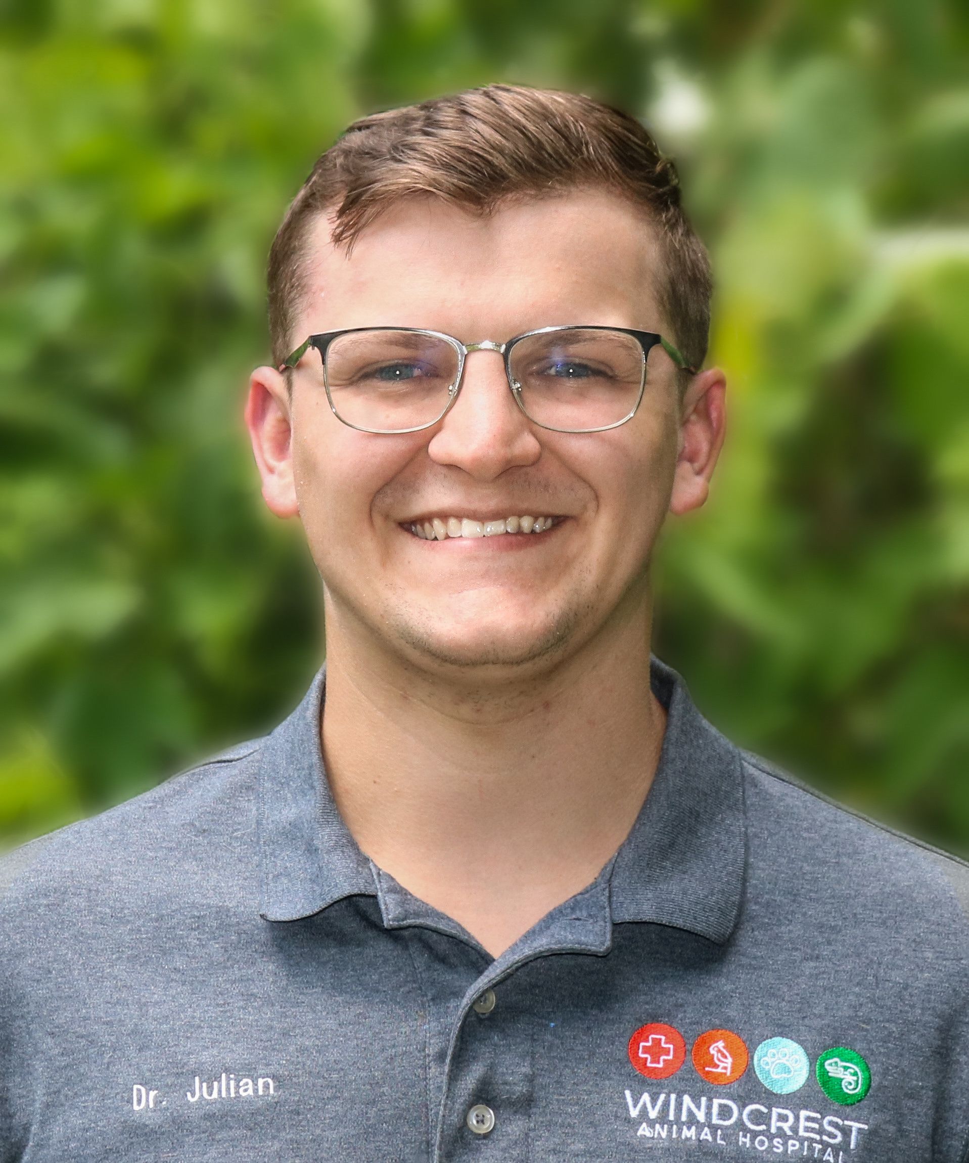 a woman in a blue shirt is smiling in front of a tree .