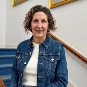 a woman in a white jacket is smiling for the camera .